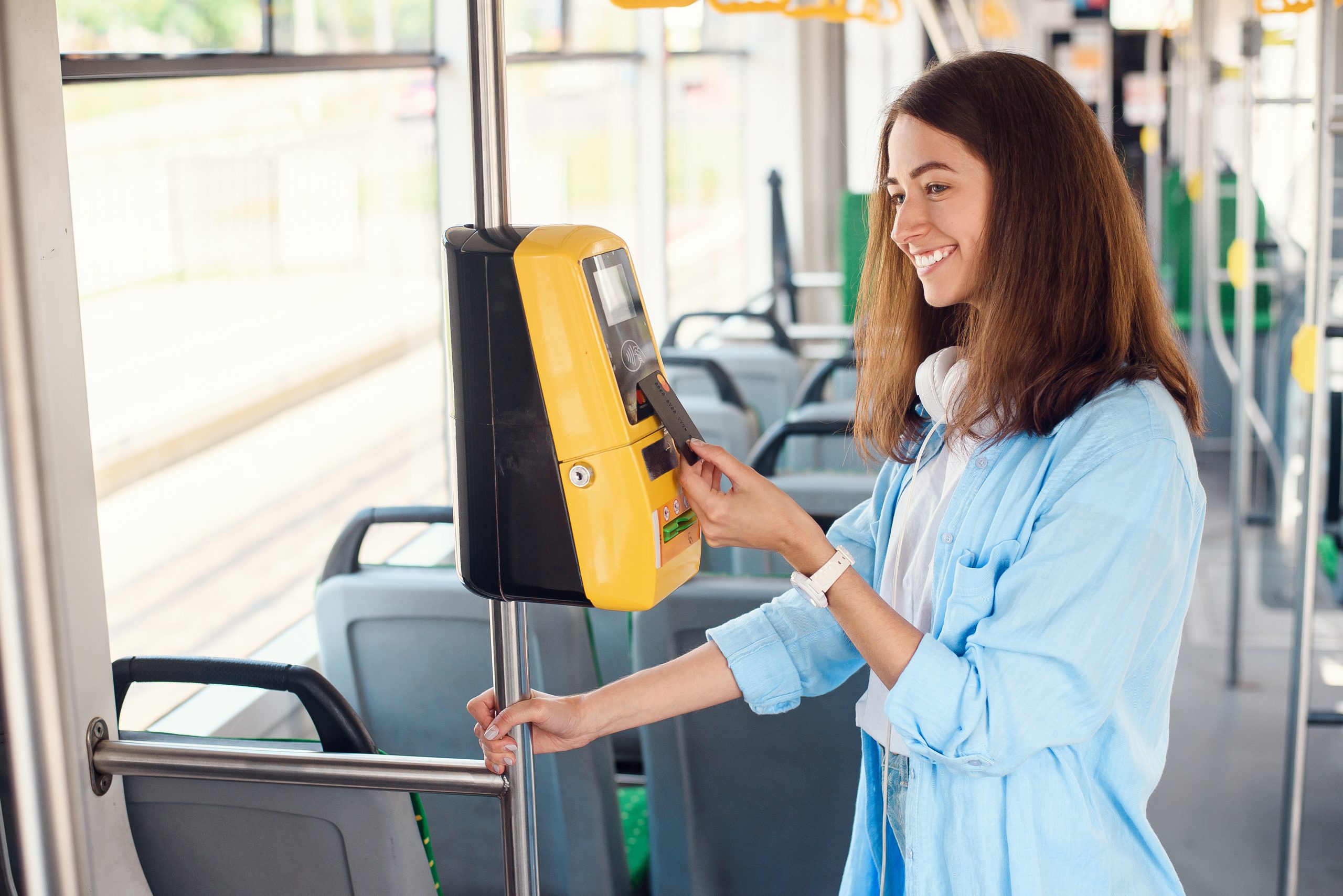 Young woman pays by bank card for the public transport in the tram or subway. Cashless payment in public transport.